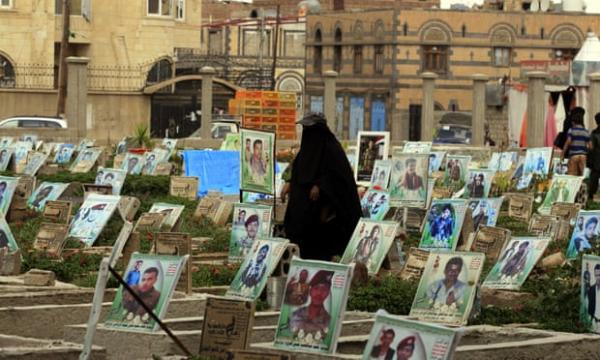 A Yemeni woman walks amongst portraits on the graves of Houthi militia members allegedly killed.jpg