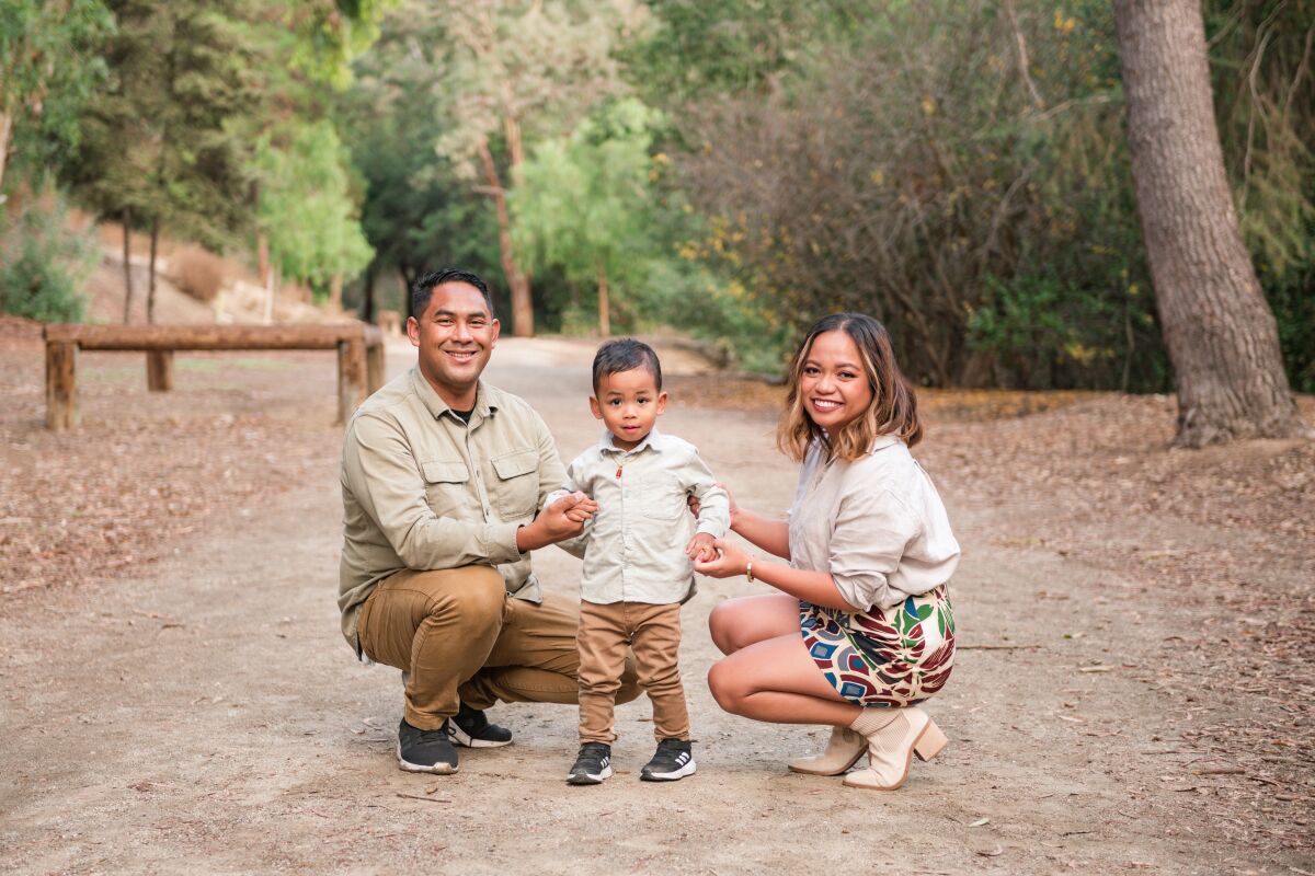 A man kneels with his son and his wife.