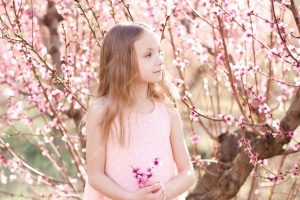 4.3-1 baby-girl-45-year-old-posing-peach-flowers-outdoors-looking-away-spring-season.jpg