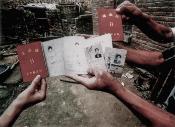 2002年，河南省新蔡县东湖村农民们手持多张卖血证。“看！这是当年的卖血证。”（高耀洁提供）.jpg