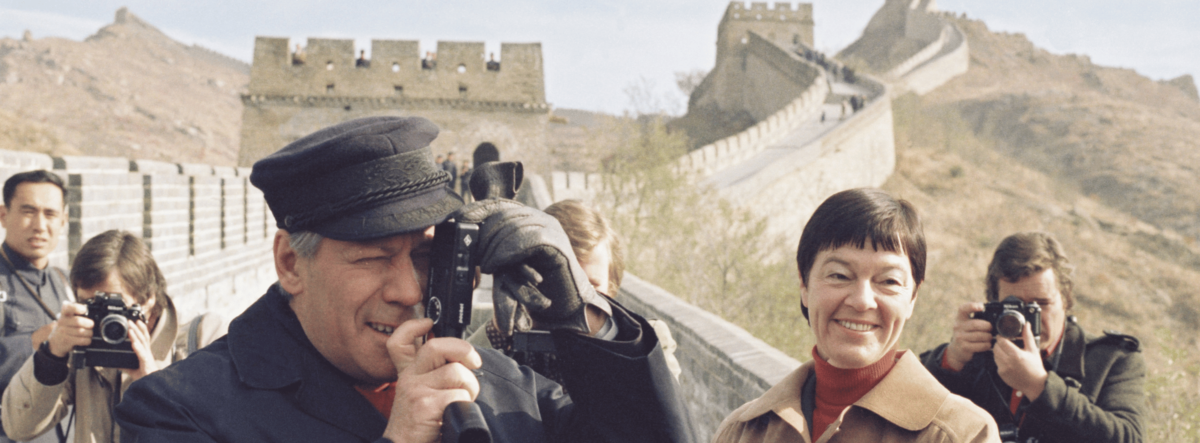 [Translate to English:] Helmut Schmidt auf der chinesischen Mauer mit einem Fotoapparat vor dem Gesicht.