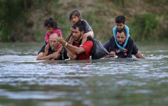 3名移民馱著兒童穿越美國得克薩斯州伊格爾帕斯附近的美墨界河格蘭德河，試圖進入美國。新華社資料圖