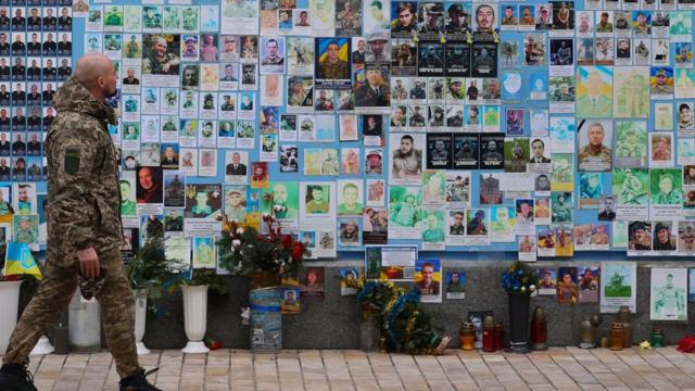 Soldier walks past memorial wall for fallen soldiers in Kyiv, 4 February 2024