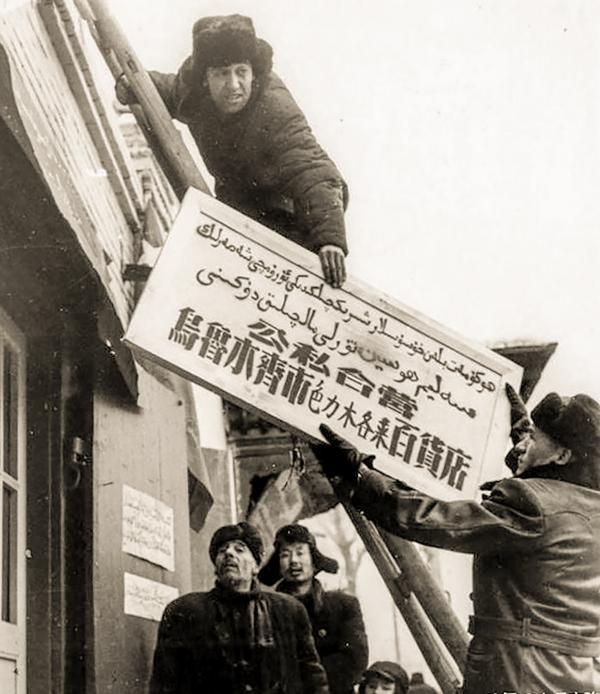 1956年1月23日，新疆乌鲁木齐市的私营工商业全部实行公私合营,乌孜别克族的色力木各来百货店被批准公私合营后，商店的人员立刻把新招牌换起来.jpg