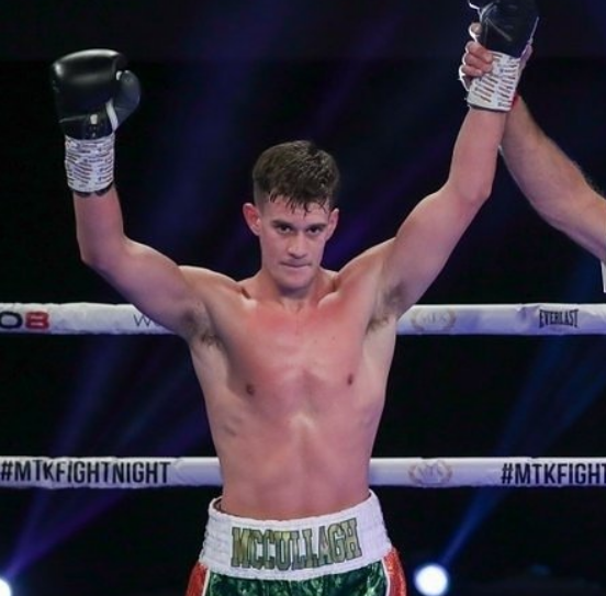 Boxer Tyrone McCullagh raising his arms in victory in the boxing ring.