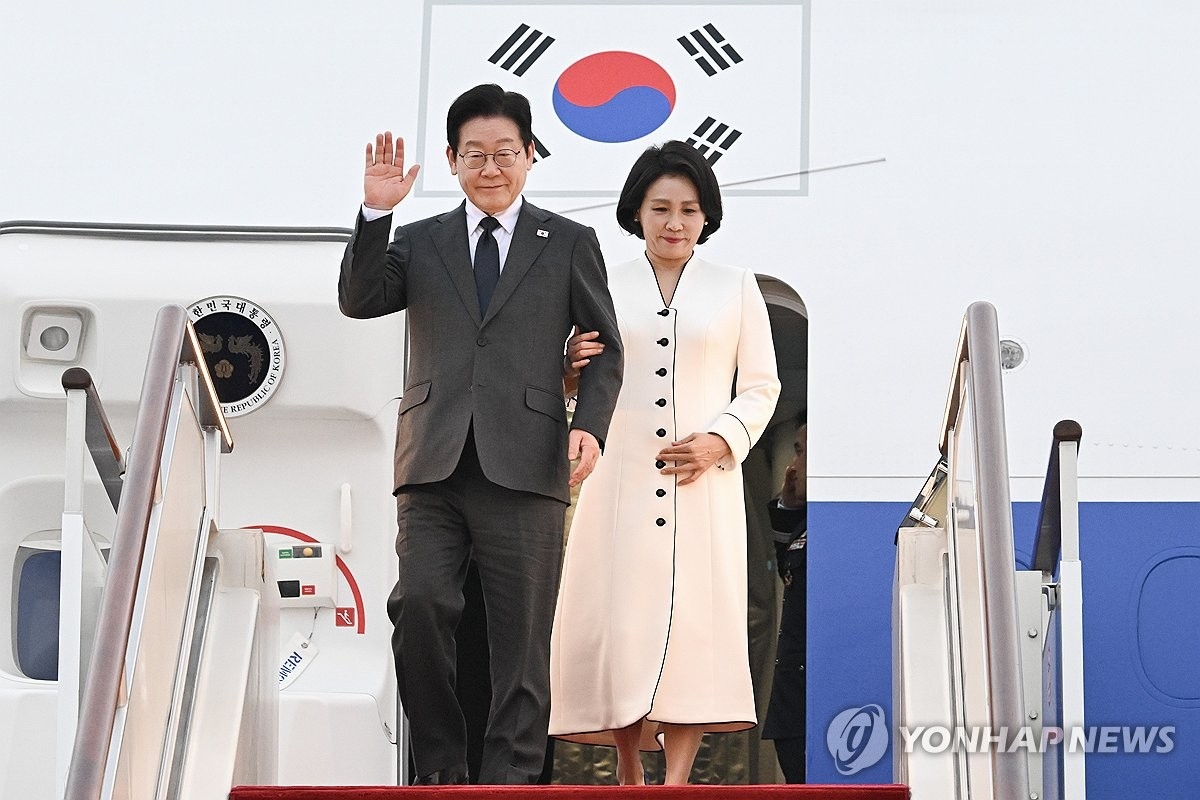 1月6日，在上海浦东国际机场，李在明（左）和夫人金惠景抵沪后向前来迎接的人士致意。 韩联社