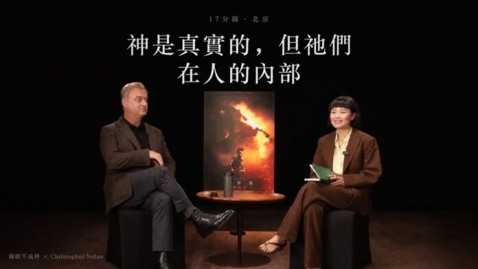 導演諾蘭與中國播客主播仲樹在北京對坐訪談，兩人之間為《奧德賽》電影海報立牌