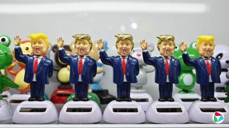 浙江义乌某展场内，五个以唐纳德·特朗普为原型、带有夸张漫画风格的人偶整齐排列在附有小型太阳能板的白色底座上。每个人偶都身穿蓝色西装、系着红色领带，并举起一只手臂。（资料图片）